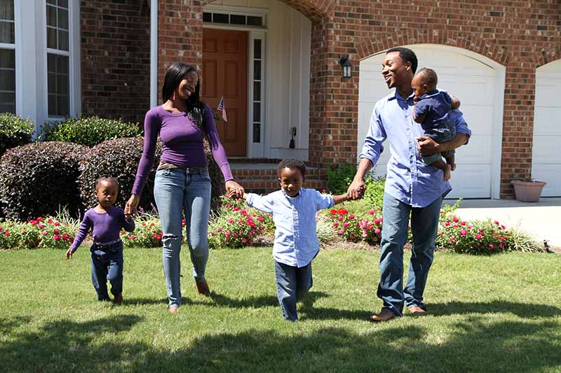 Parents walking with their child in the front lawn of their new home